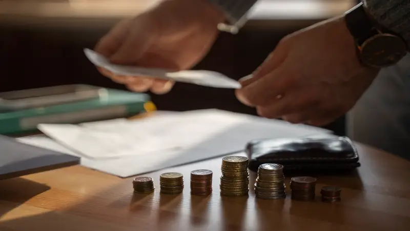 Mãos organizando moedas sobre a mesa para ilustrar como cobrar honorários de forma estratégica e justa